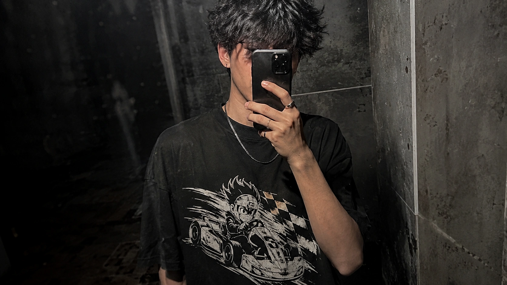 Mirror selfie of a young man in a black graphic T-shirt holding a phone